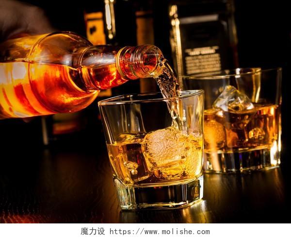 酒保倒在威士忌玻璃和木桌上的瓶威士忌